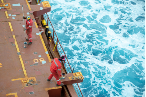 Two crew members in orange coveralls working on deck